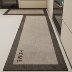 Tapis d'entrée gris avec motifs et inscription "HOME" et "WOHH" visible sur un sol blanc dans une cuisine.