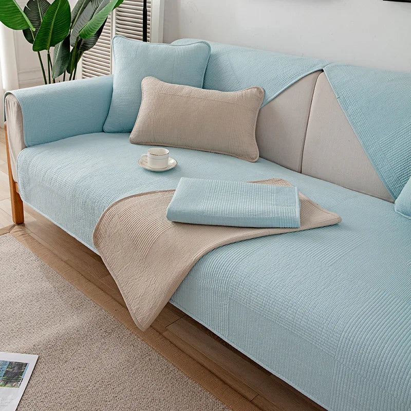 Un canapé moderne et confortable dans des tons de bleu et de beige, avec des coussins et une couverture assortis, créant une ambiance chaleureuse et apaisante dans cette pièce.