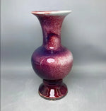 Vase décoratif en céramique brillante de couleur violette et rose, avec une forme élancée et un motif texturé.