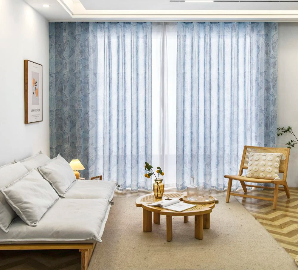 Voilage grande largeur à ruflette bleu clair installé dans un salon lumineux au style scandinave.