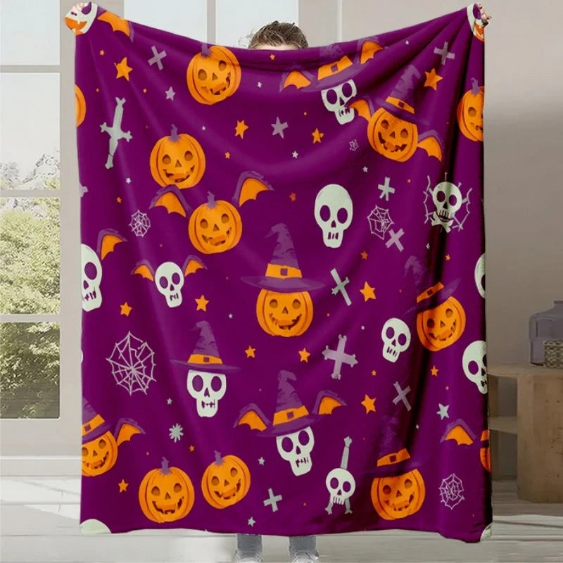 Une couverture en polaire violette colorée avec des motifs d'Halloween incluant des citrouilles, des crânes et des chapeaux de sorcière.