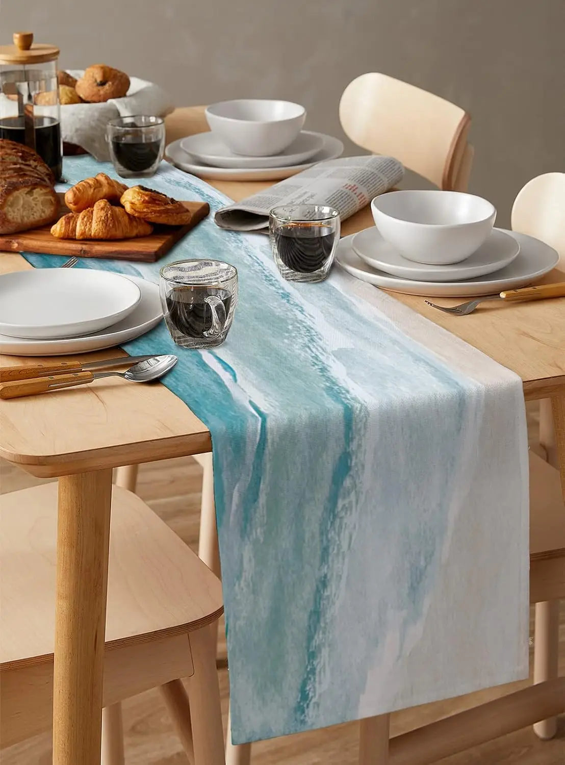 Une table dressée avec des plats, des boissons et des ustensiles, soulignée par un chemin de table décoratif aux tons bleutés, offrant un aperçu d'un repas convivial.