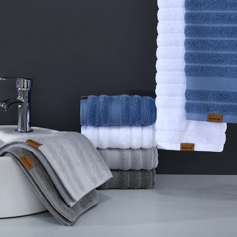 Serviettes de bain bleu et blanc sur étagère, salle de bain moderne avec robinet et lavabo.