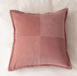 Un coussin rose en velours côtelé, avec un motif géométrique contrasté, offrant une touche de douceur et d'élégance à l'espace.
