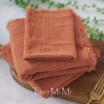 Des serviettes de table en lin orange vif empilées sur une surface en bois, créant une composition naturelle et texturée.