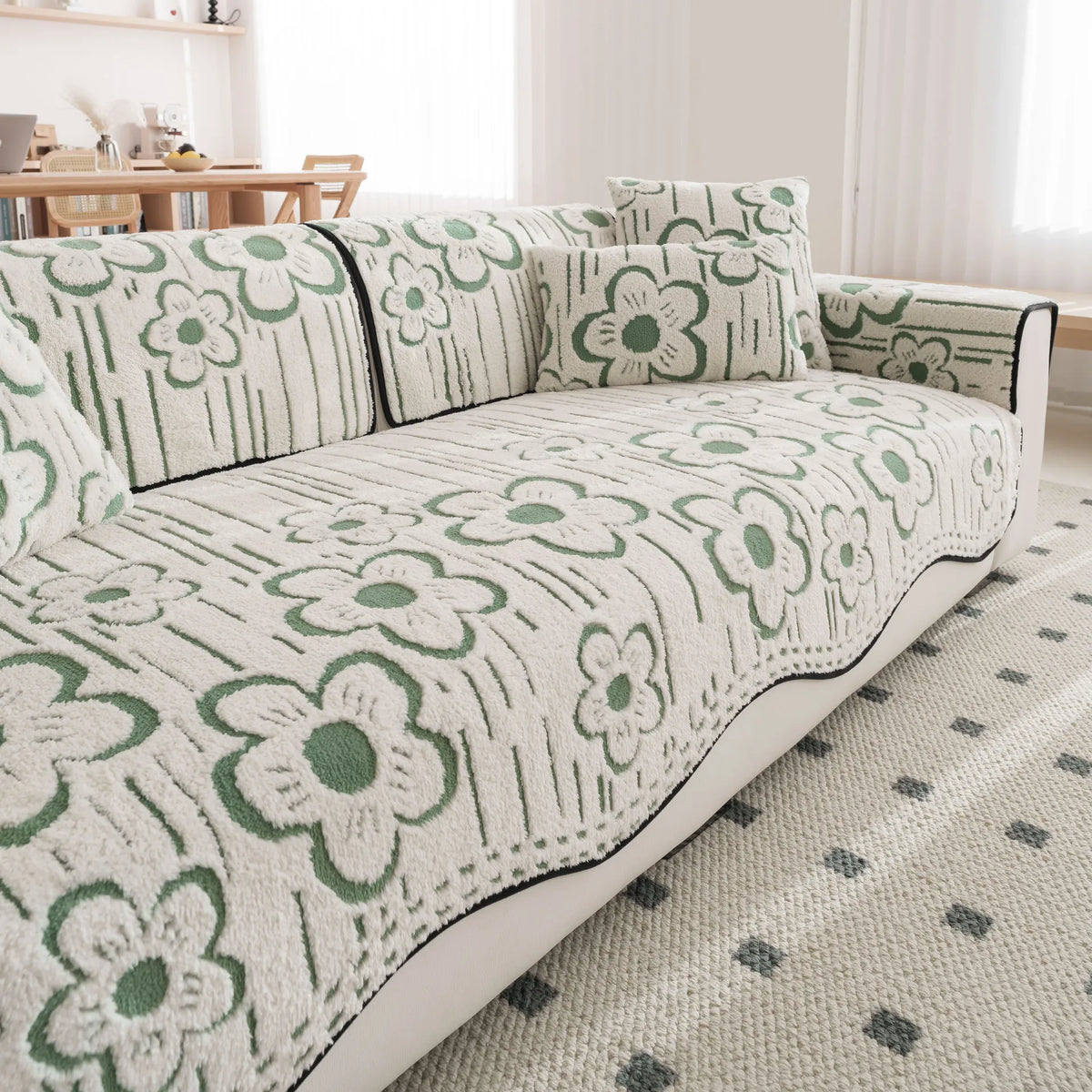 Un canapé confortable avec un motif floral vert et blanc, dans une ambiance chaleureuse et cosy.