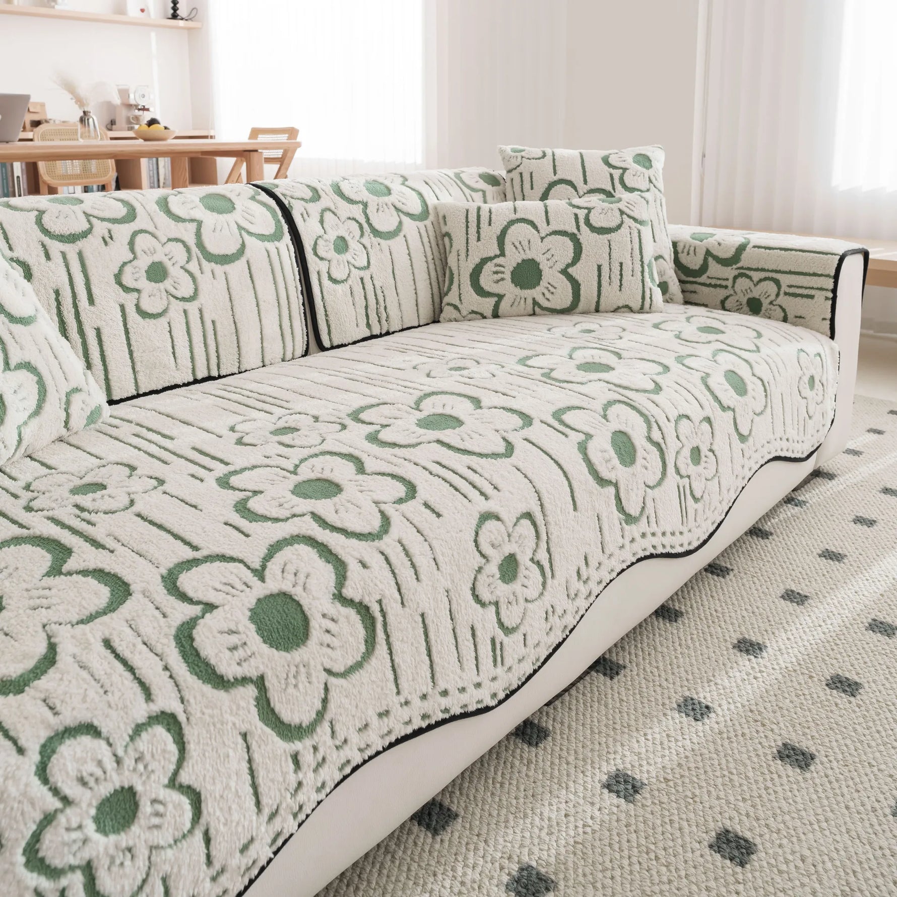 Un canapé confortable avec un motif floral vert et blanc, dans une ambiance chaleureuse et cosy.