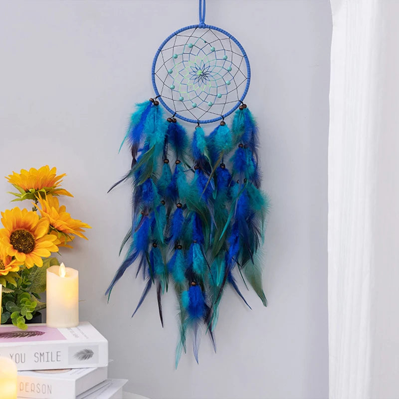 Capteur de rêves aux tons bleus et verts, décoré de plumes aux couleurs éclatantes, suspendu à côté de tournesols et d'une bougie.