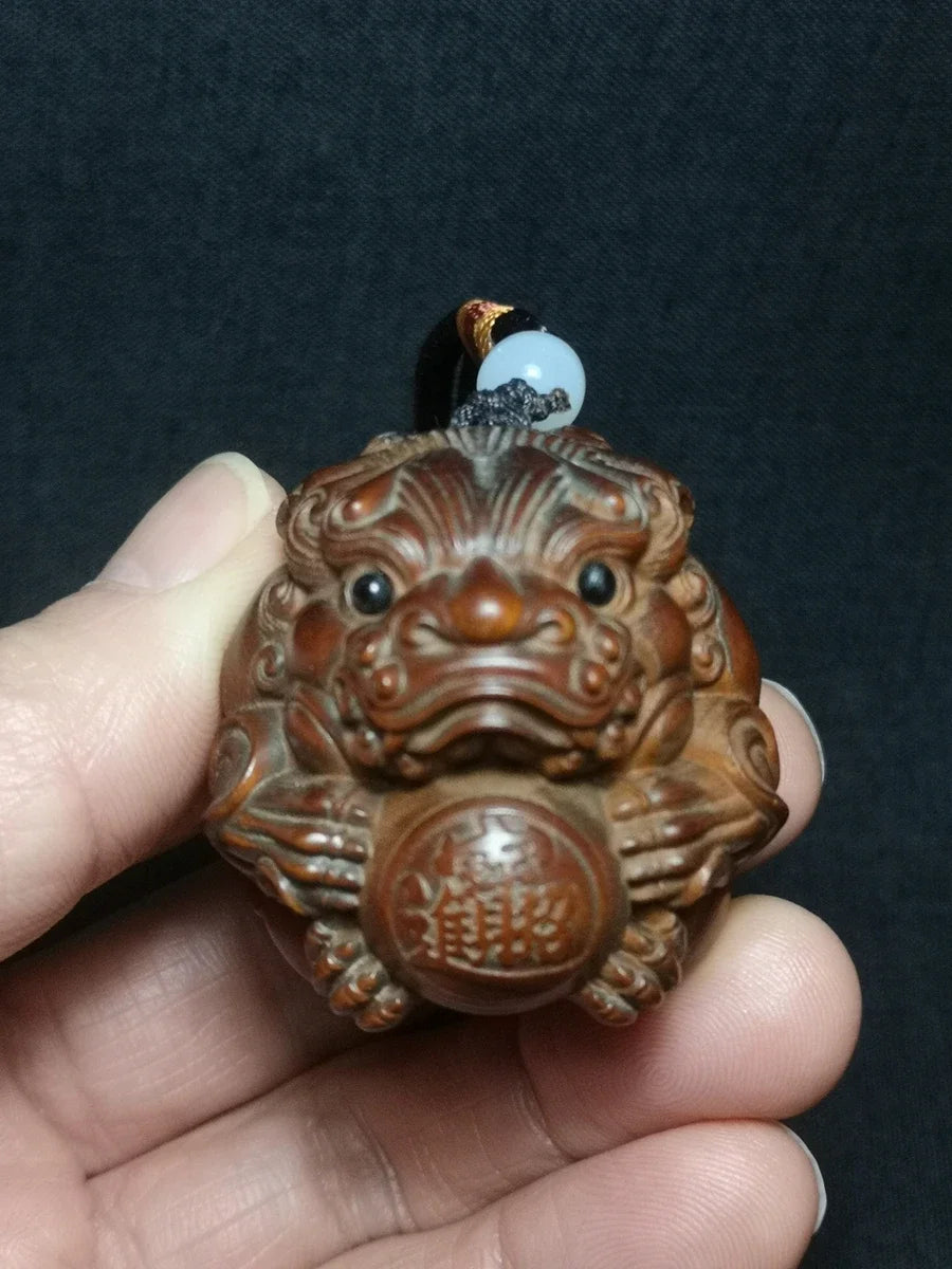 pendentif sculpté lion globe caractères chinois motifs floraux artisanal traditionnel yeux noirs