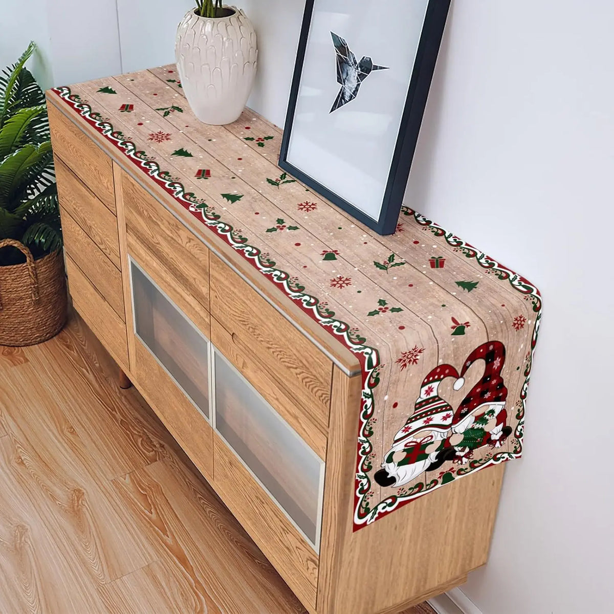 Un meuble en bois décoré d'un motif festif avec des gnomes, des flocons de neige et des feuilles de houx, créant une ambiance chaleureuse et de fête.