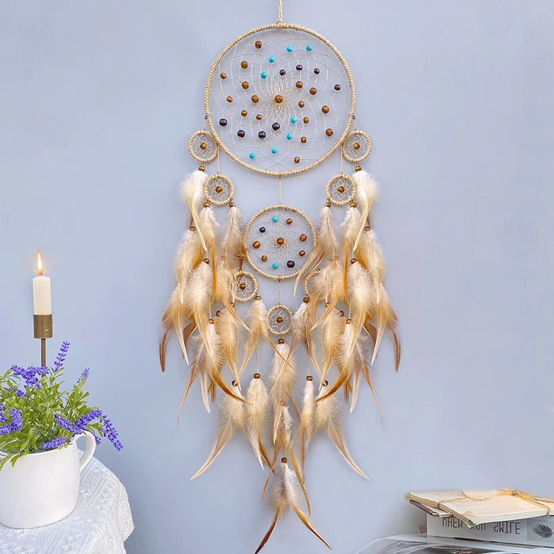 Un rêve attrapeur décoratif en plumes naturelles avec des perles et des pierres semi-précieuses suspendues sur un fond bleu clair.