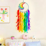 Un capteur de rêves arc-en-ciel composé de plumes colorées suspendu sur un mur blanc, accompagné de décorations de chambre d'enfants.
