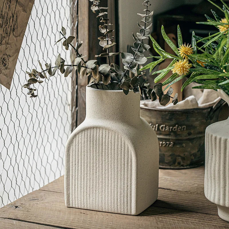 vases céramique relief blanc cassé lignes verticales fleurs artificielles eucalyptus branches fleurs jaunes arrangement