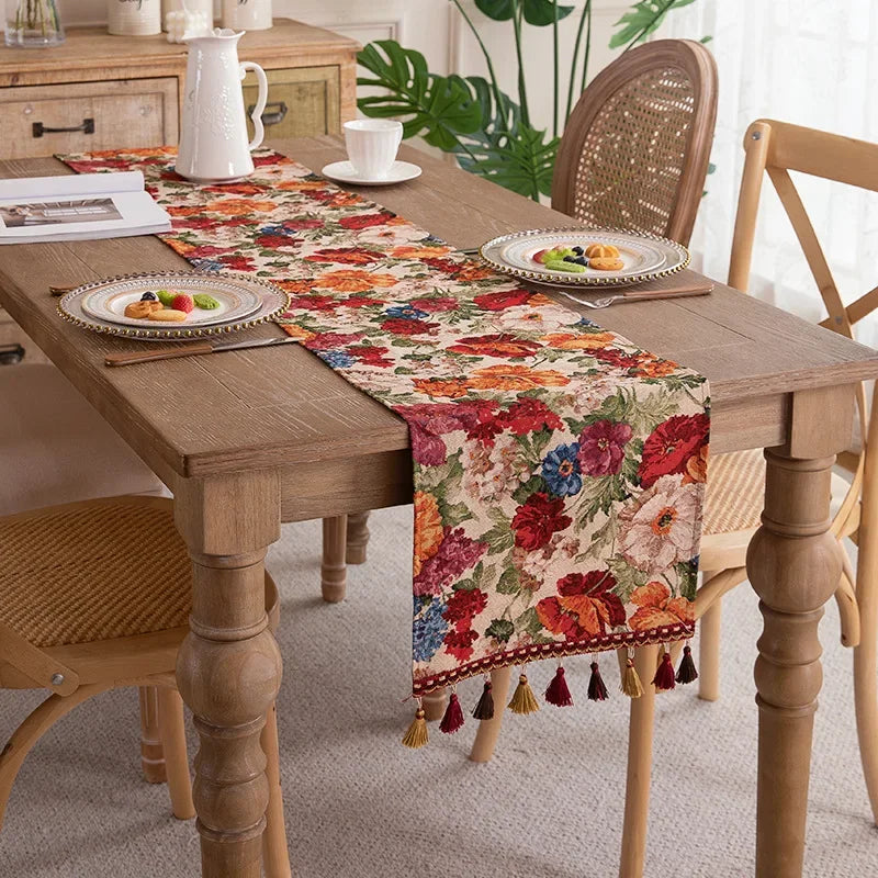 Une table à manger rustique avec un élégant chemin de table fleuri, des assiettes et des accessoires de décoration qui apportent une touche chaleureuse et bohème à cet espace de repas.