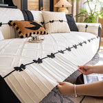 Élégant canapé avec des oreillers décoratifs noirs et blancs dans un cadre verdoyant.