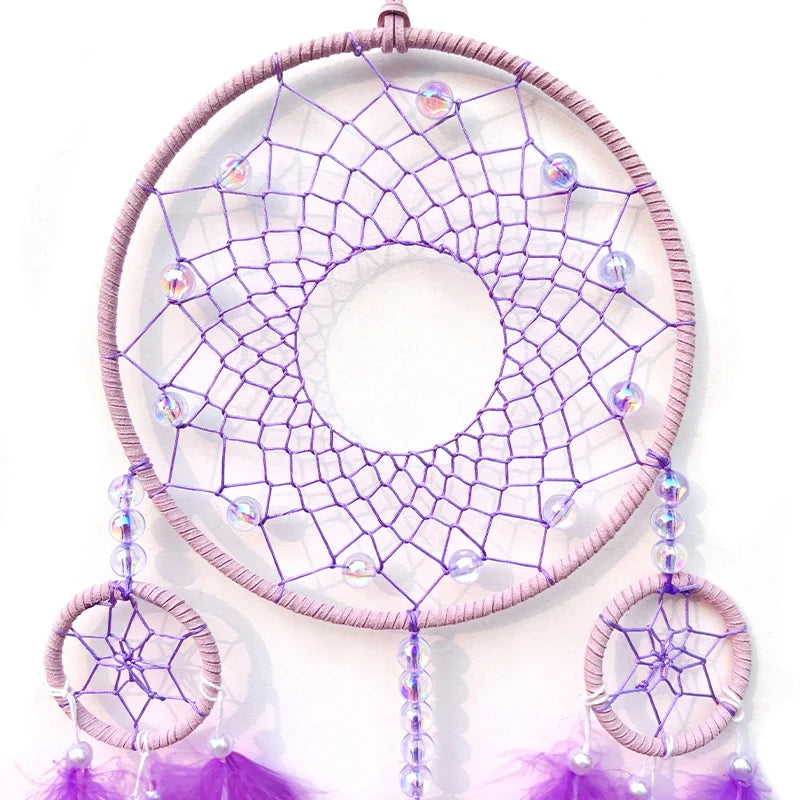 Un attrape-rêves violet orné de perles colorées et de plumes violet pâle, créant une composition délicate et apaisante.