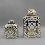 Ces deux récipients décorés de motifs géométriques noirs et or sur un fond blanc apportent une touche de design graphique élégant.