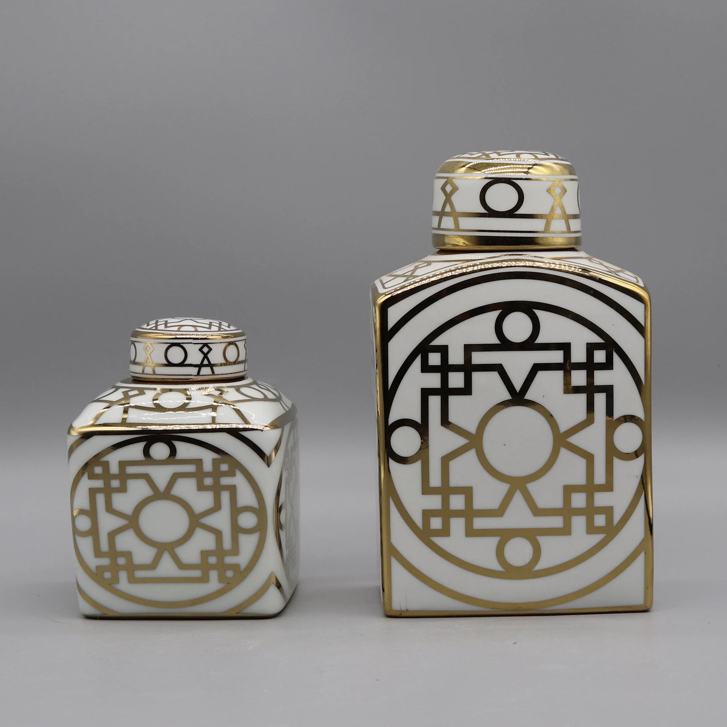 Ces deux récipients décorés de motifs géométriques noirs et or sur un fond blanc apportent une touche de design graphique élégant.