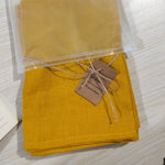 Serviettes en lin pur emballées et étiquetées, dans une couleur jaune moutarde vive.