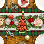 Une table de fête joliment décorée avec des ornements de Noël et des mets festifs, comprenant notamment un arbre de Noël fait de fraises et des boules rouges et blanches.