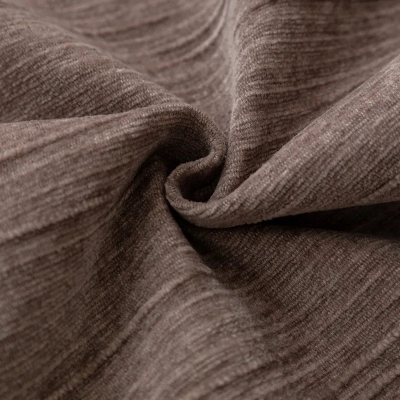 Texture en gros plan d'un tissu brun-gris plissé, créant un motif ondulé et une sensation de chaleur et de confort.