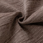 Texture en gros plan d'un tissu brun-gris plissé, créant un motif ondulé et une sensation de chaleur et de confort.