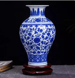 Magnifique vase en porcelaine bleu et blanc décoré de motifs floraux élégants posé sur un socle en bois.