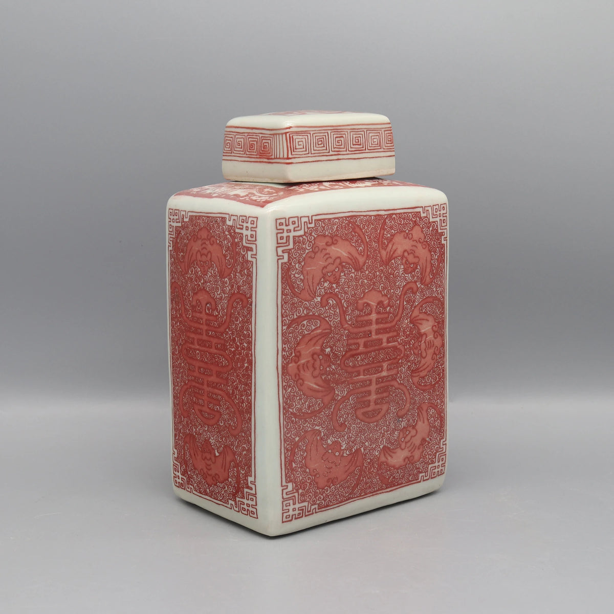 Un vase en céramique décoré de motifs asiatiques élégants et complexes dans des tons rouges et crème.