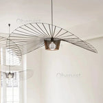 Lustre suspension rotin noir allumé dans une cuisine moderne