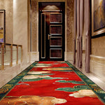 Un couloir élégant avec un tapis rouge et des motifs orientaux, menant à une porte en bois sombre décorée.