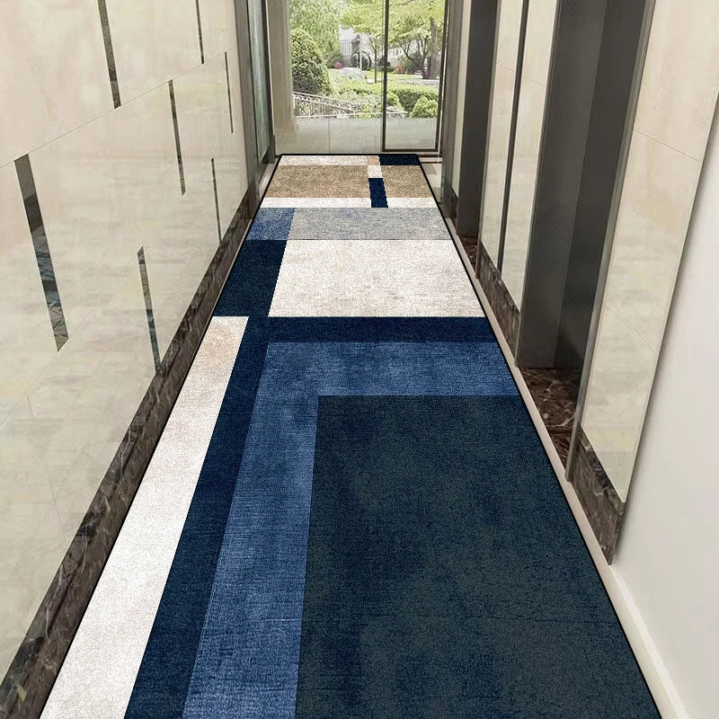 Le couloir moderne est décoré avec un motif géométrique bleu et gris sur le sol, reflétant la lumière naturelle qui entre par les grandes baies vitrées.