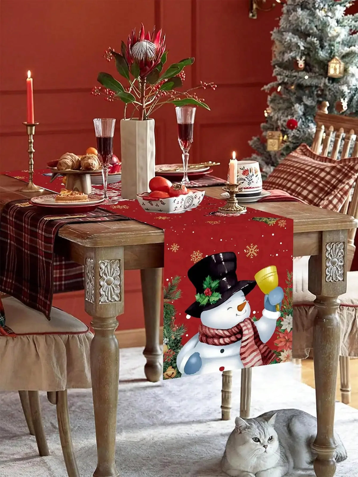 Une scène hivernale festive avec une table décorée de chandelles, de fleurs et de verres de vin, et un magnifique bonhomme de neige sur la nappe.