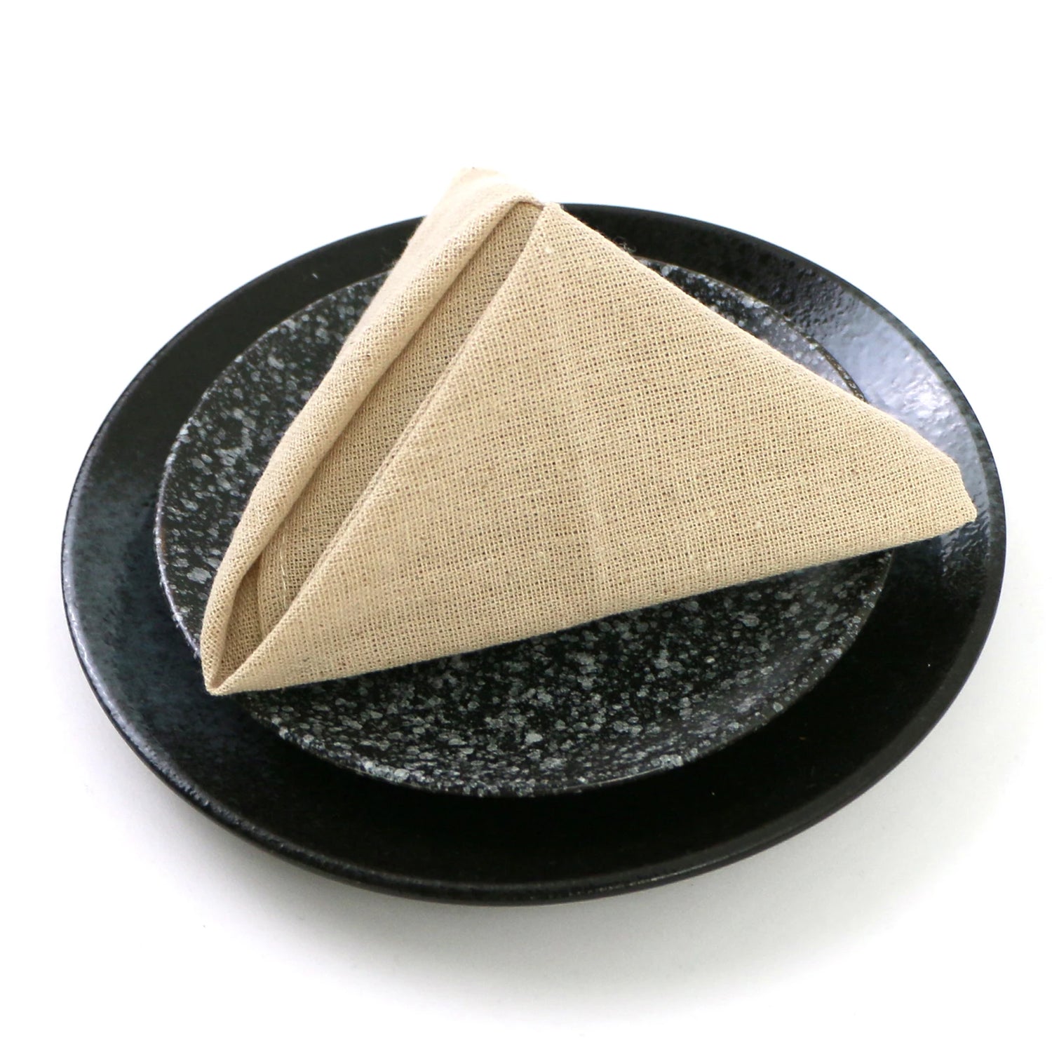 Un serviette beige pliée de manière élégante sur une assiette noire texturée.