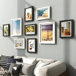 Ensemble de 9 cadres photo en bois naturel sur un mur blanc