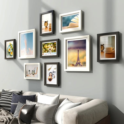 Ensemble de 9 cadres photo en bois naturel sur un mur blanc