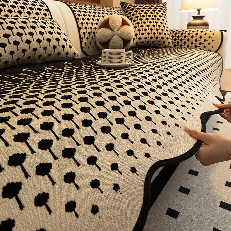 Gros plan sur un lit recouvert d'une couverture noire et blanche aux motifs graphiques géométriques, avec des coussins assortis.