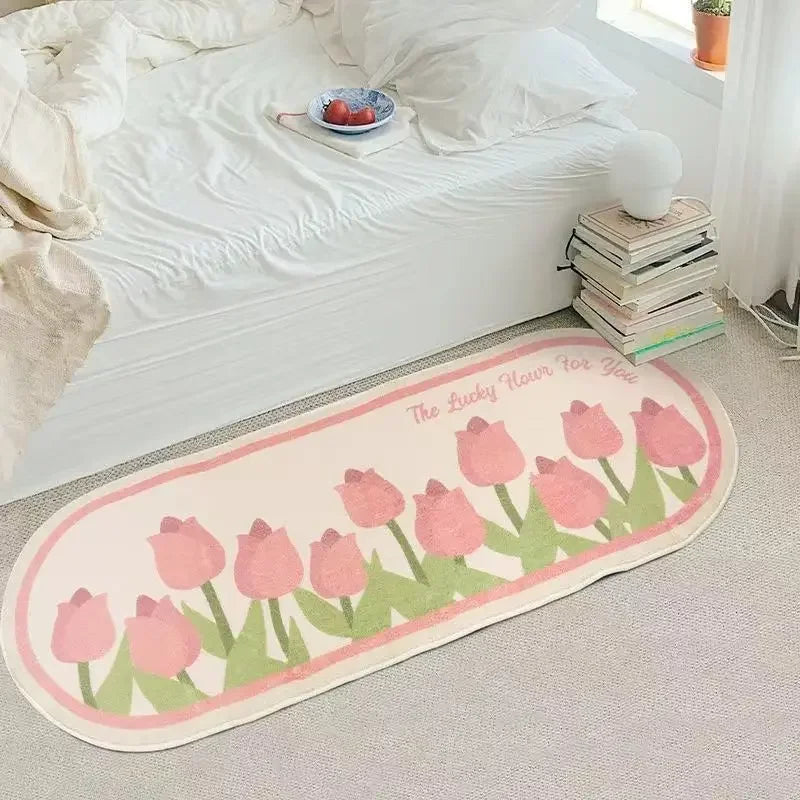 Un tapis orné de tulipes roses sur le sol d'une chambre avec un lit, des livres et une plante.