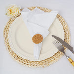 Composition élégante avec une assiette blanche, des couverts et une fleur sur un dessous de plat en osier tressé.