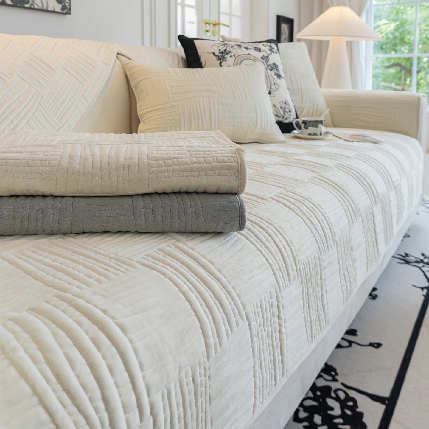 Une chambre confortable avec des draps et des oreillers matelassés en ton beige et gris, créant une atmosphère apaisante.