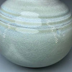 Vase en céramique gris-bleu avec un motif décoratif en relief sur la surface.