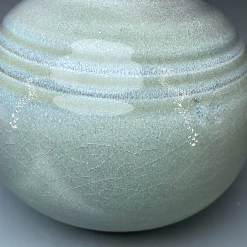 Une élégante urne de porcelaine avec une surface texturée en motifs concentriques irisés, donnant une impression de pureté et de raffinement.