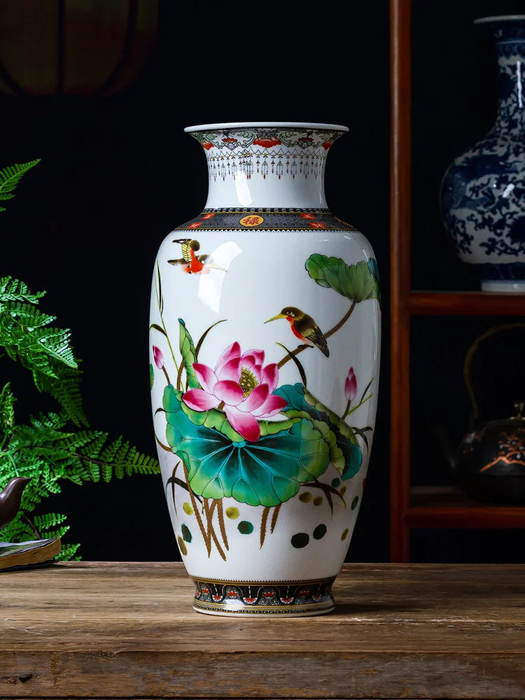 Vase en porcelaine blanc décoré de fleurs de lotus roses, de feuilles vertes et d'un oiseau coloré, sur une table en bois.