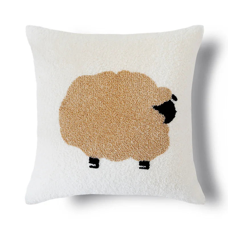 Un coussin blanc avec un mouton brun et noir en motif appliqué.
