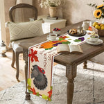 Une belle table de salon couverte d'un chemin de table décoré de feuilles d'automne et d'un beau poulet, accompagnée de fruits et d'un livre ouvert, créant une ambiance chaleureuse et confortable.