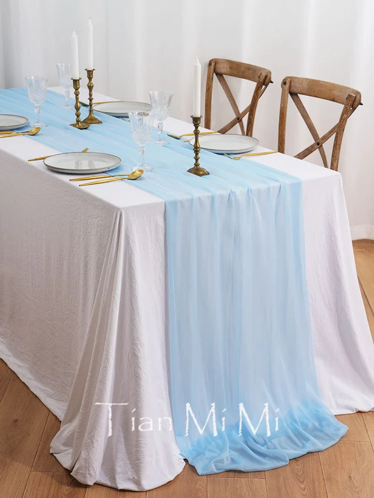 L'image montre une table de salle à manger élégante, avec une nappe bleue délicate, des bougies, des verres et des couverts dorés. Une ambiance chic et raffinée pour un repas entre amis ou en famille.
