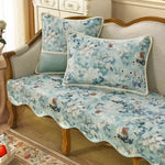 Ce canapé vintage en bois doré est recouvert d'un motif floral délicat dans des tons de bleu et de vert, créant une ambiance de charme et de fraîcheur dans cette pièce.