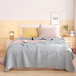 Une chambre à coucher élégante avec un lit double, une couverture rayée grise et blanche, des oreillers beiges et une décoration de style scandinave.