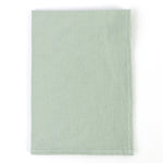 Linge de table vert clair, avec des points blancs discrets le long des bords, suggérant une texture douce et chic.