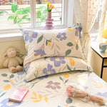 Une chambre lumineuse et accueillante, décorée de motifs floraux colorés sur les coussins et la literie, créant une ambiance chaleureuse et sereine.