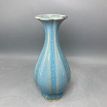 Un vase en céramique de forme élancée et allongée, avec un fini craquelé en nuances de bleu clair et foncé, créant un effet élégant et distinctif.